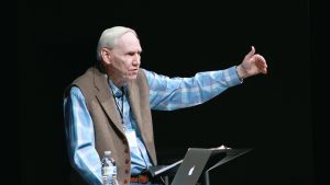 Dr. Howard Eyrich lifted hand, preaching, black background