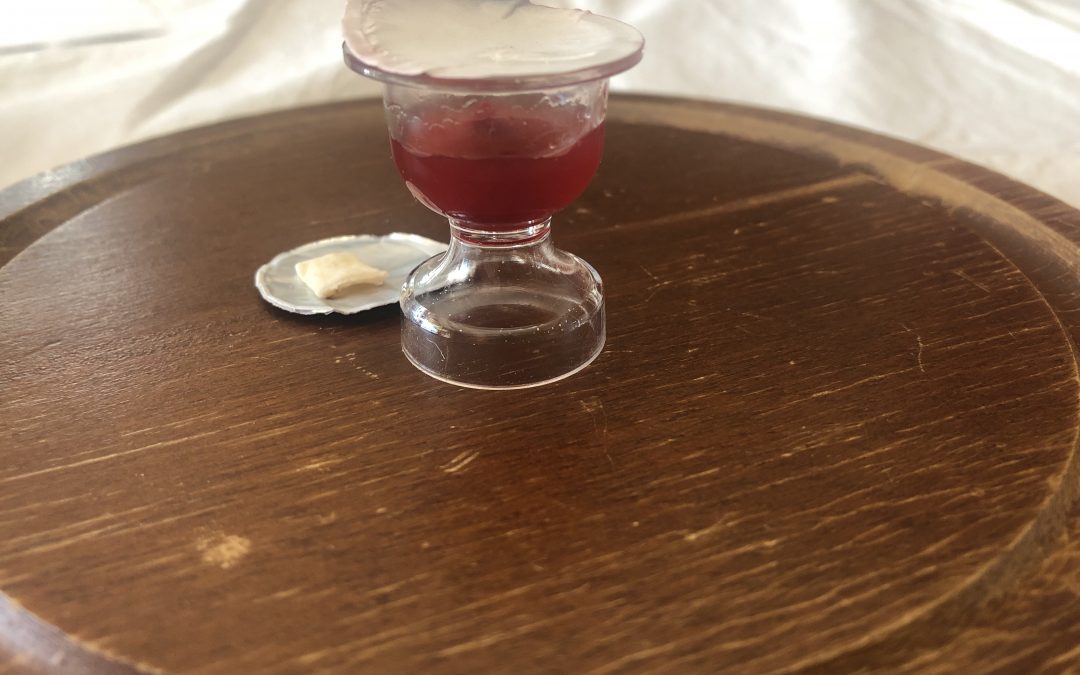 opened communion cup and flat cracker on flat communion board platter