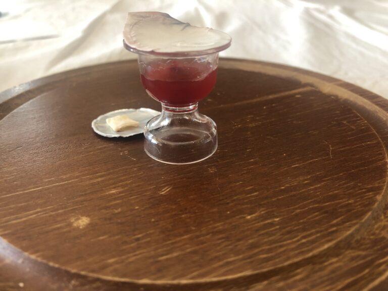opened communion cup and flat cracker on flat communion board platter